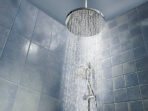 Low angle of running water from shower head in a cool coloured shower
