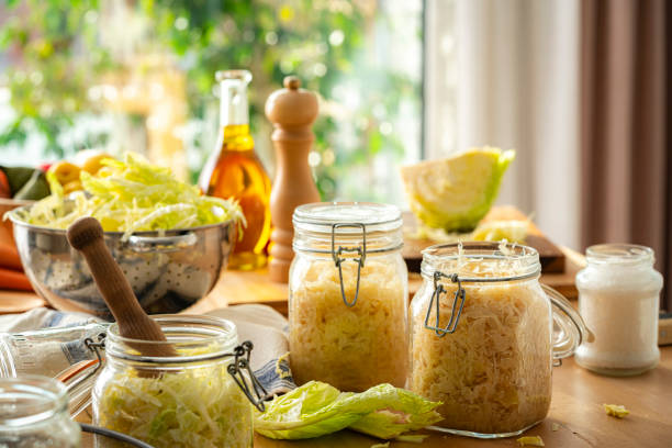 Homemade sauerkraut in glass jars and fresly shredded cabbage on kitchen table