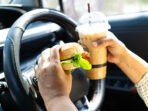 Asian woman driver hold and eat hamburger and cold coffee in car.