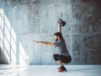 Male fitness athlete performing overhead squat with kettlebell